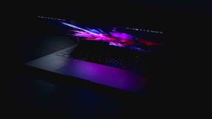 Computer laptop slightly open with purple and pink colors